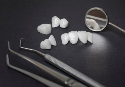 Several dental veneers and crowns resting on table with dental instruments