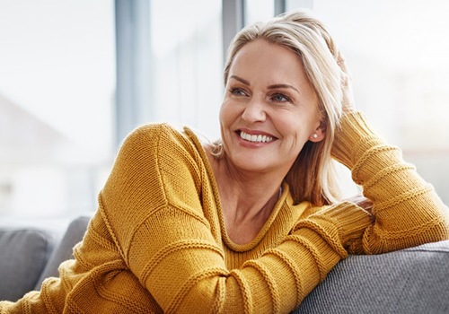 a woman smiling and relaxing on her couch