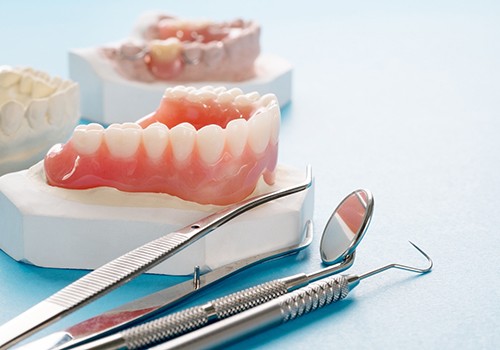 Set of dentures on a cast next to dental instruments