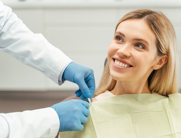 A dentist preparing a smiling blonde woman for dental treatment