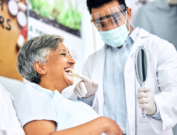 Patient smiling at reflection in handheld mirror