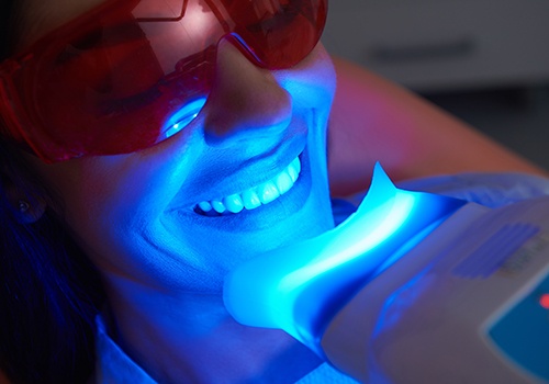 Woman having teeth whitened with dentist